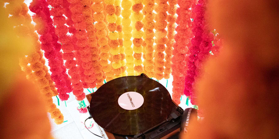 A record player sits inside a cylinder made from strings of flowers.
