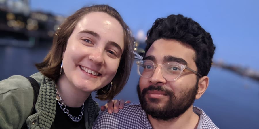 Hannah and her boyfriend stand in front of the sea.