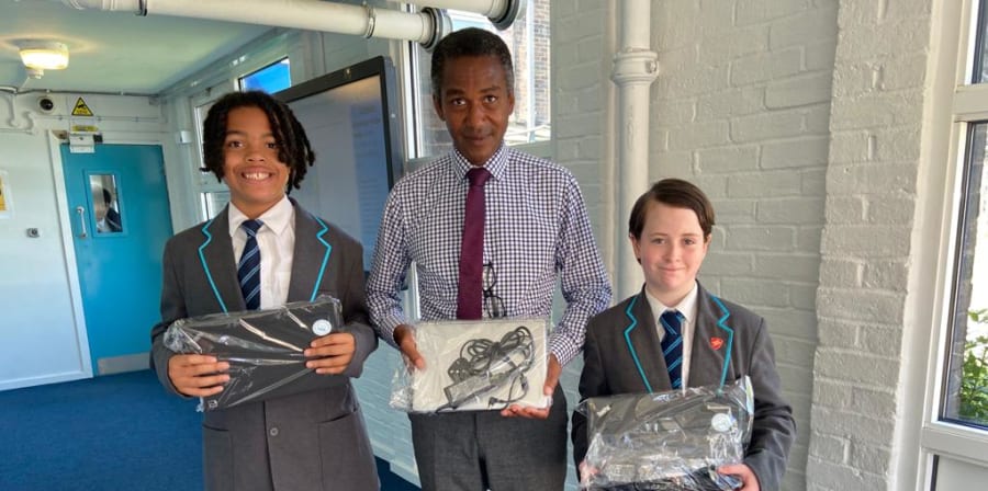 Photo of two students and one teacher holding new laptops