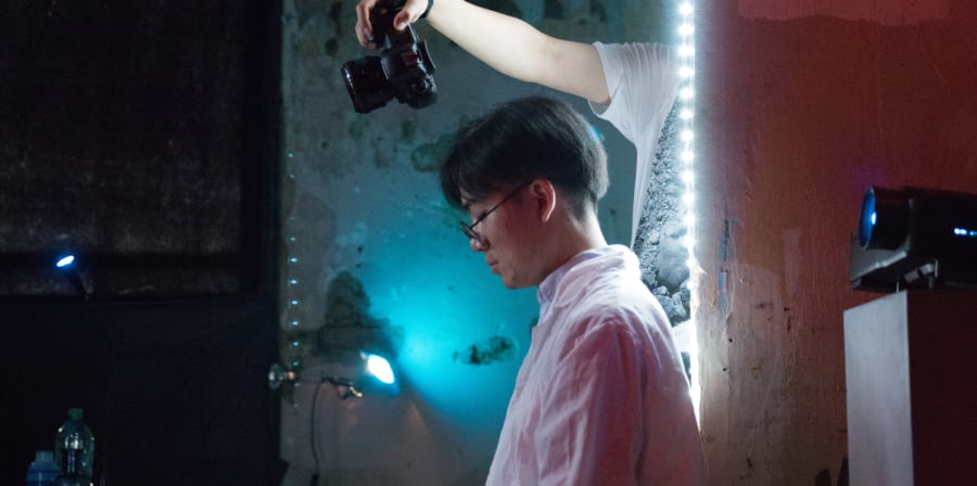 Student holding a camera with a blue light in the background