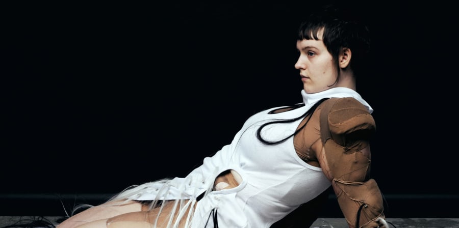 An editorial fashion shot of a styled model in kneeling position.