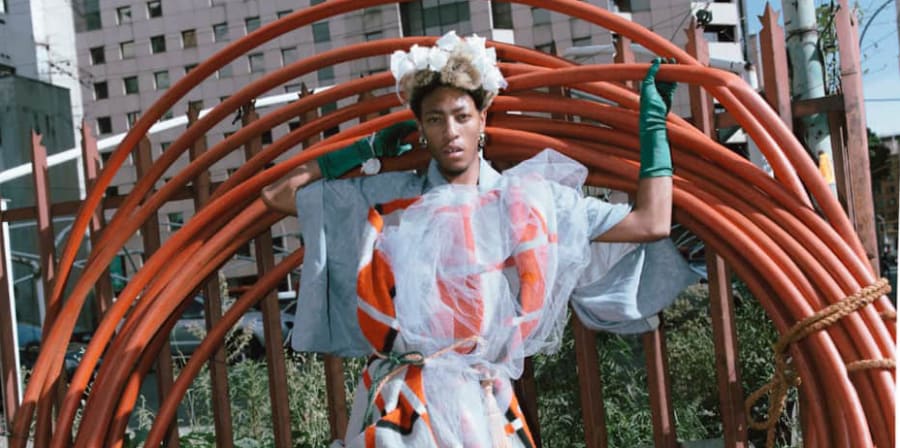 A person wearing a dress with orange details, posing with a set of large orange wheels