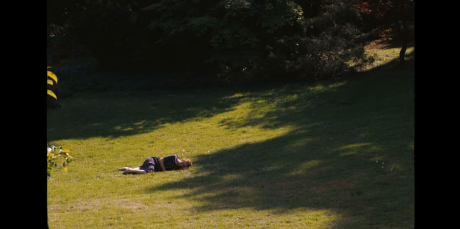 A girl lies on green grass.