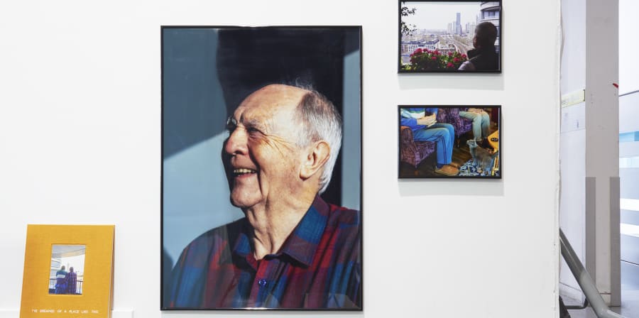 A series of exhibited photos including a portrait of an older man laughing.
