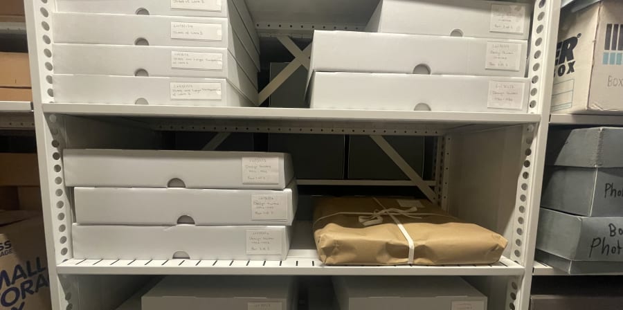 Light grey archival boxes stacked over three shelves. 