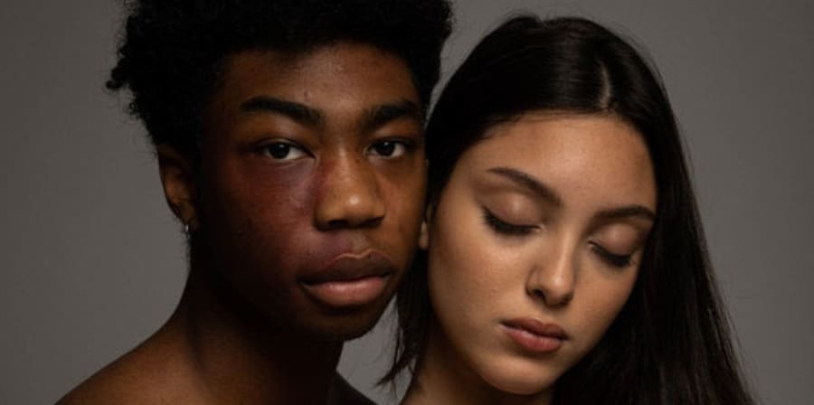 A warm-toned photograph of two models staring at the camera.