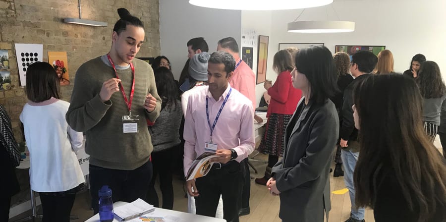 A group of students and audience members peer at project assets.