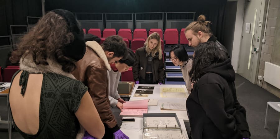 Staff and students looking at material from an archives collection on tables in a cinema space