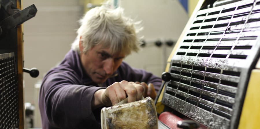 A person pouring ink into a printing press