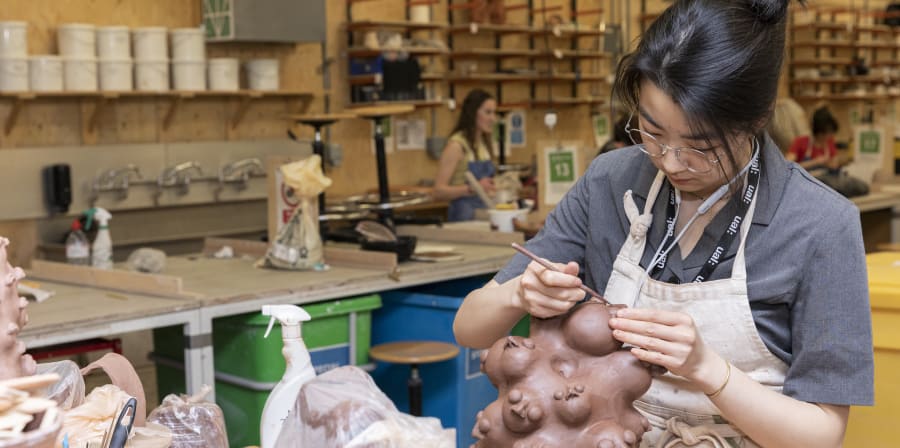 Students working with clay and ceramic pieces on display inside the Ceramics Workshop at Central Saint Martins