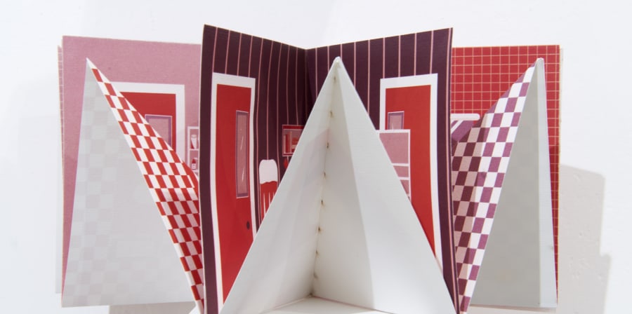 Close-up of a piece of student work - a folded paper shape with red printed patterns on the inside.
