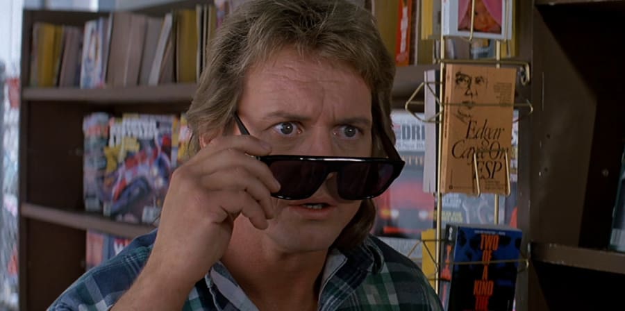 Man with blonde hair removing sunglasses with shocked look on his face.