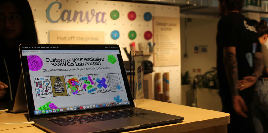 Photograph of a laptop on a desk, with the screen showing poster designs.