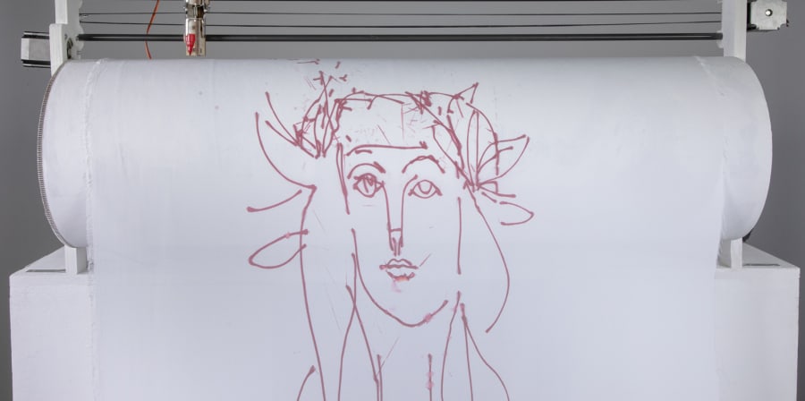 A robot holding sheet of fabric with a drawing of a Picasso-style face, with the sheet of paper on a roller with a pen held