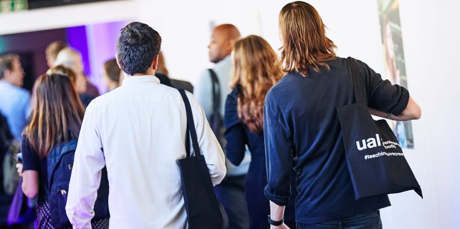 People holding tote bags walking along a corridor