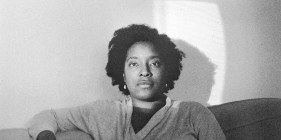A woman stares at the camera while sitting on a sofa.
