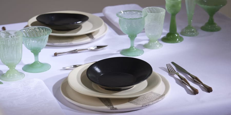 A table with a white table cloth set with plates, cutlery and glassware