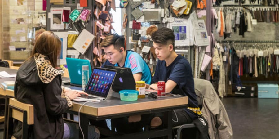 Group of students studying in a library. Mixed media resources are shown behind