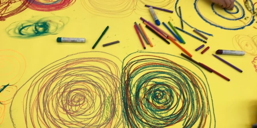 yellow paper shows hands scribbling colour pencil circles