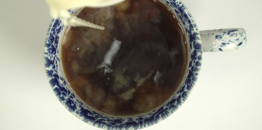 A still of milk being poured into a teacup.