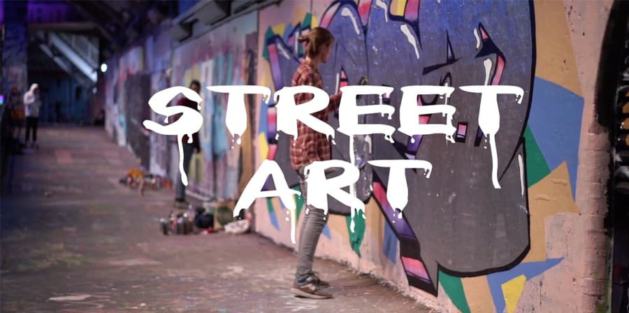 A still from a student film which reads 'Street Art' in white text against a background featuring a graffiti wall.