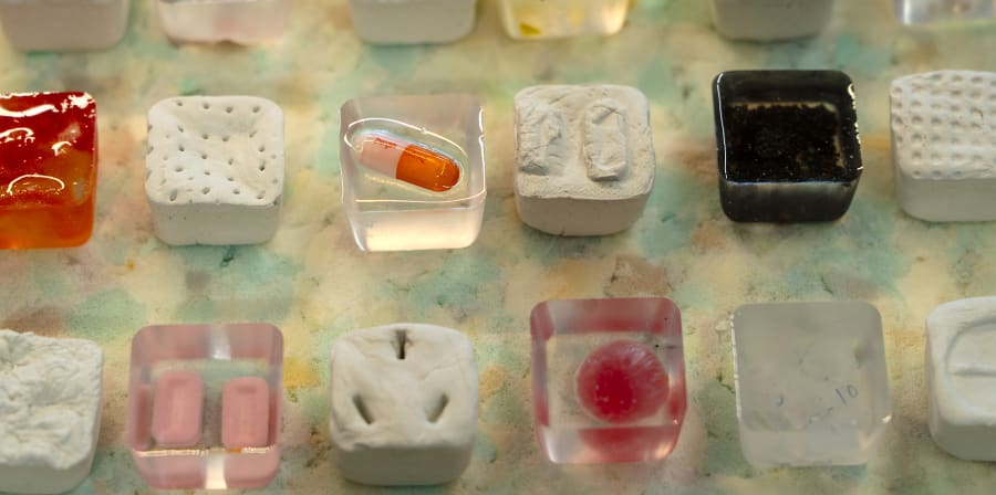 A selection of small resin blocks in different colours some containing different shaped pills