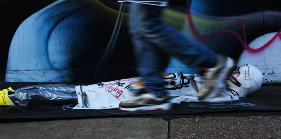 sculpture of a mummy on floor with handwritten notices and stickers about fashion