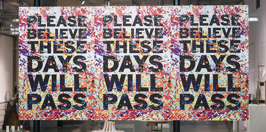Three posters on a window which say 'These days will pass'