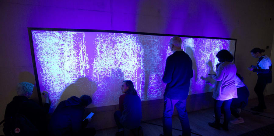 People standing in front of a screen in a purple-lit room 