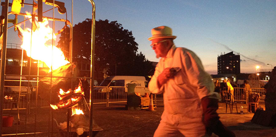 A man stood next to a large trolly which has a fire inside of it