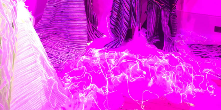 clear mannequins in a brightly lit, pink neon coloured room