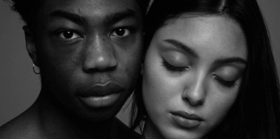 A black and white photograph of two models, one of whom has closed their eyes.