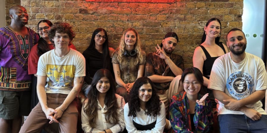 A diverse group of MA students smile joyfully, celebrating their recent work.