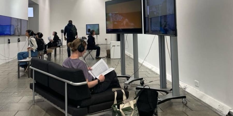 People enjoying the audio-visual works at an exhibition hall.