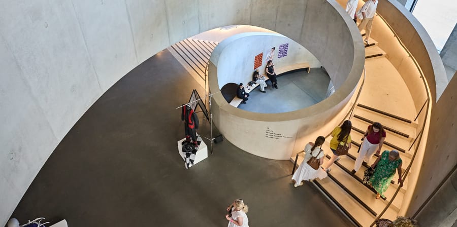 People in and on the large curved concrete staircase and atrium at LCF East Bank.