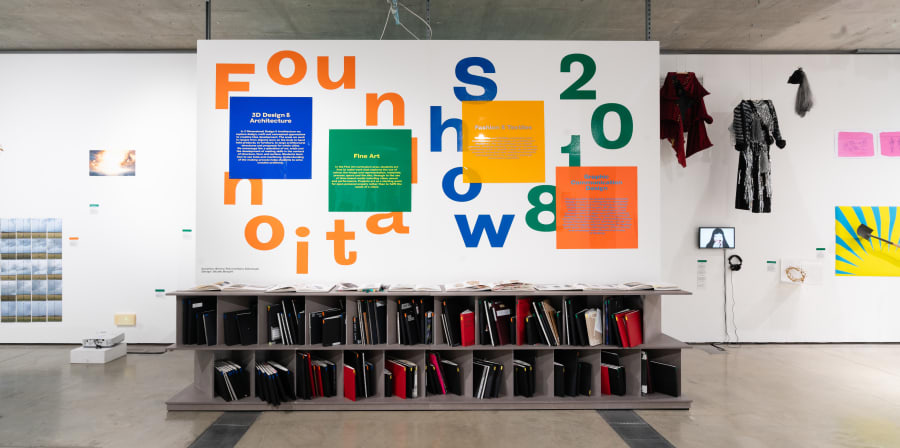 Work on display in a gallery, Foundation Show 2018 is written on the wall is bold green, orange and blue letters