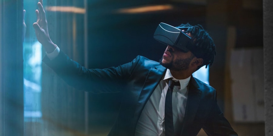 Image shows a man in a suit wearing a VR headset.