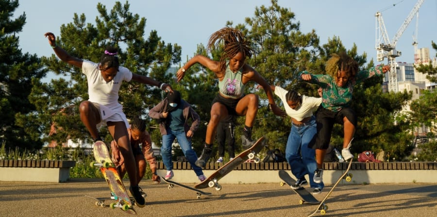 Female skaters performing tricks at a park.