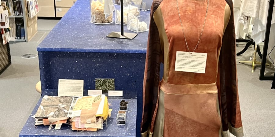 Display showing a dress died in a variety of natural colours including oranges and browns