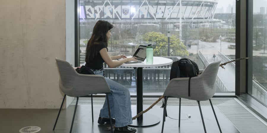 Someone sitting at a table working on their laptop