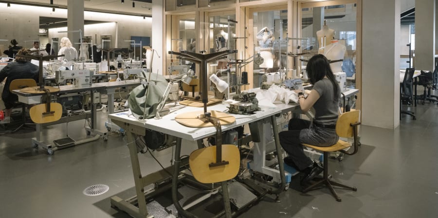 Person using sewing machine at table.