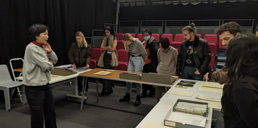 Staff and students looking at material from an archives collection on tables in a cinema space