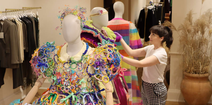 Curator Zoe Buckberry adjusting a graduation robe for Grayson Perry on the shop floor.