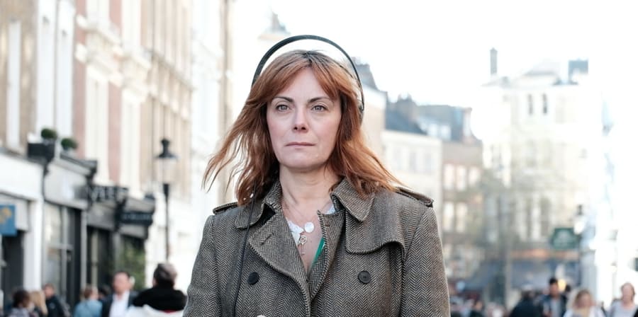 Photo of woman in street holding her phone with headphones on