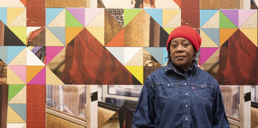 Artist Sonia Boyce standing in front of a wall with multicoloured triangular shapes. 