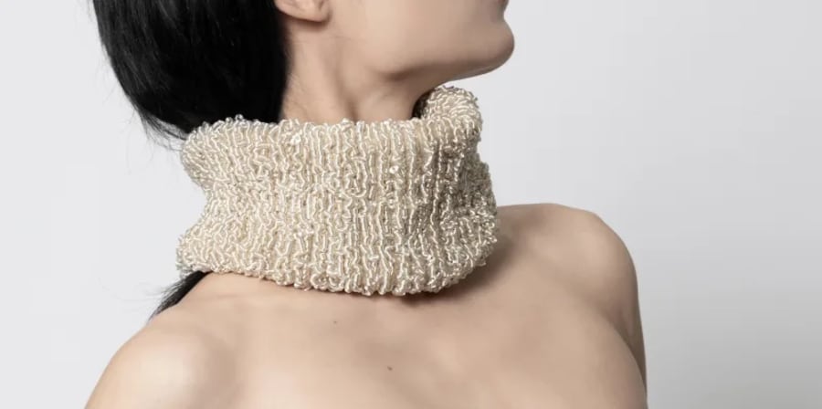 A person wearing an intricate silver neck cuff