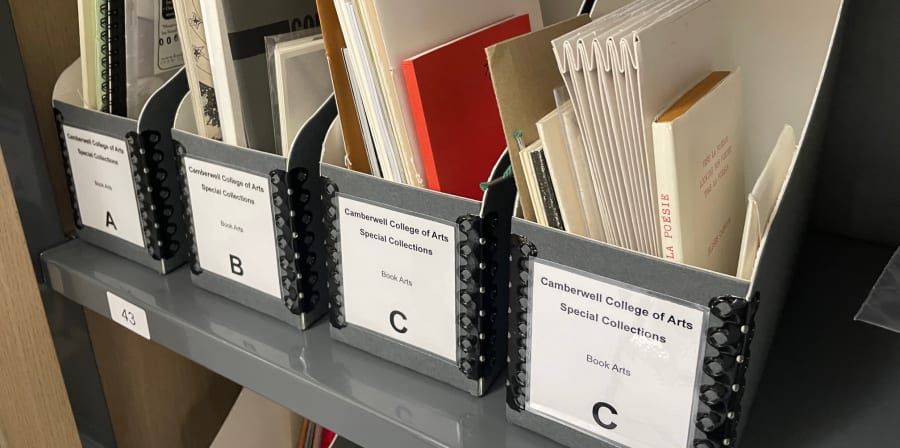 Colour photograph of small books and booklets in conservation friendly blue grey box files, with tidy labels on them