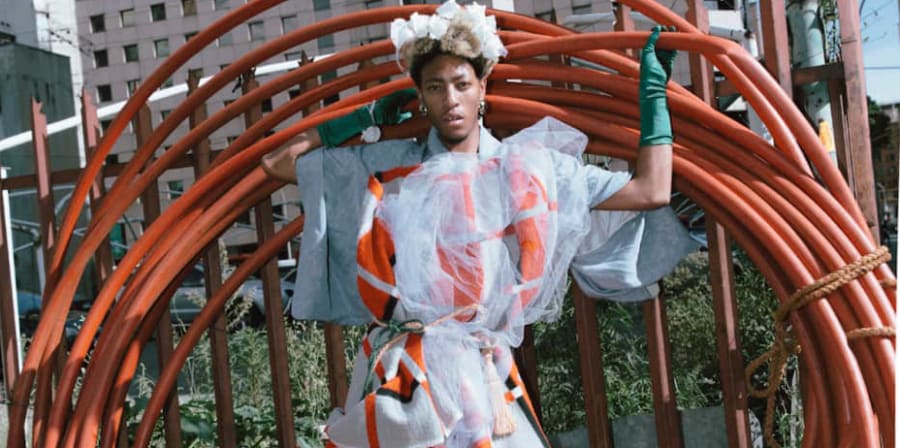 A person wearing a dress with orange details, posing with a set of large orange wheels