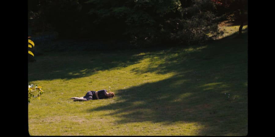 A girl lies on green grass.