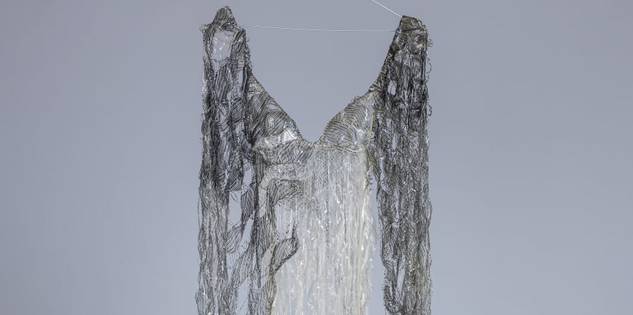 A black and grey transparent dress made of plastic materials with repeated holes throughout.